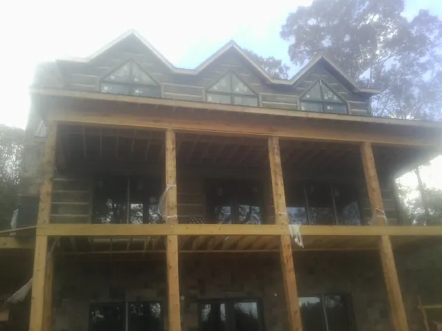 Dormers and porch framing on a large log home under construction — Roof Coating work by our crew in Siloam