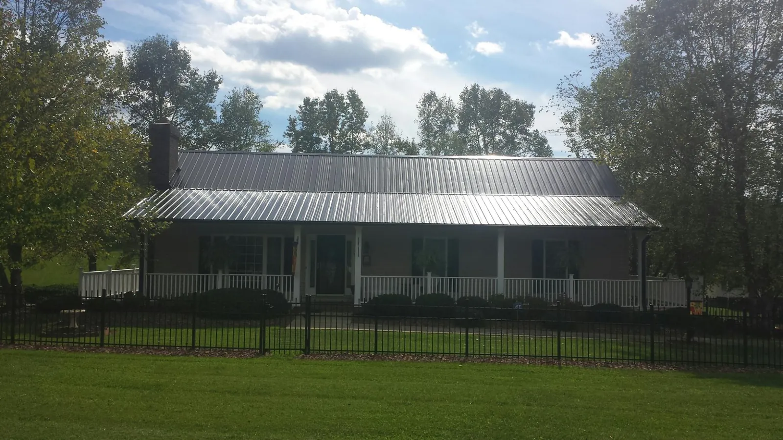 Gray metal roof on a brick ranch with a full width front porch — Gutter Guard Installation work by our crew in Siloam